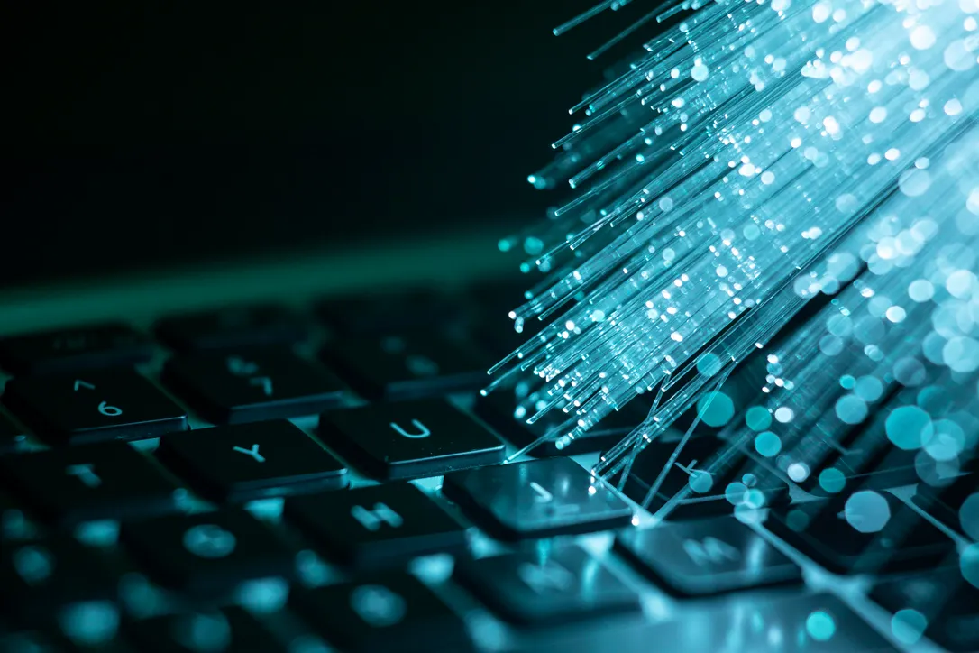 Gros plan sur clavier d'ordinateur avec visualisation de flux de données numériques et effets lumineux cyan