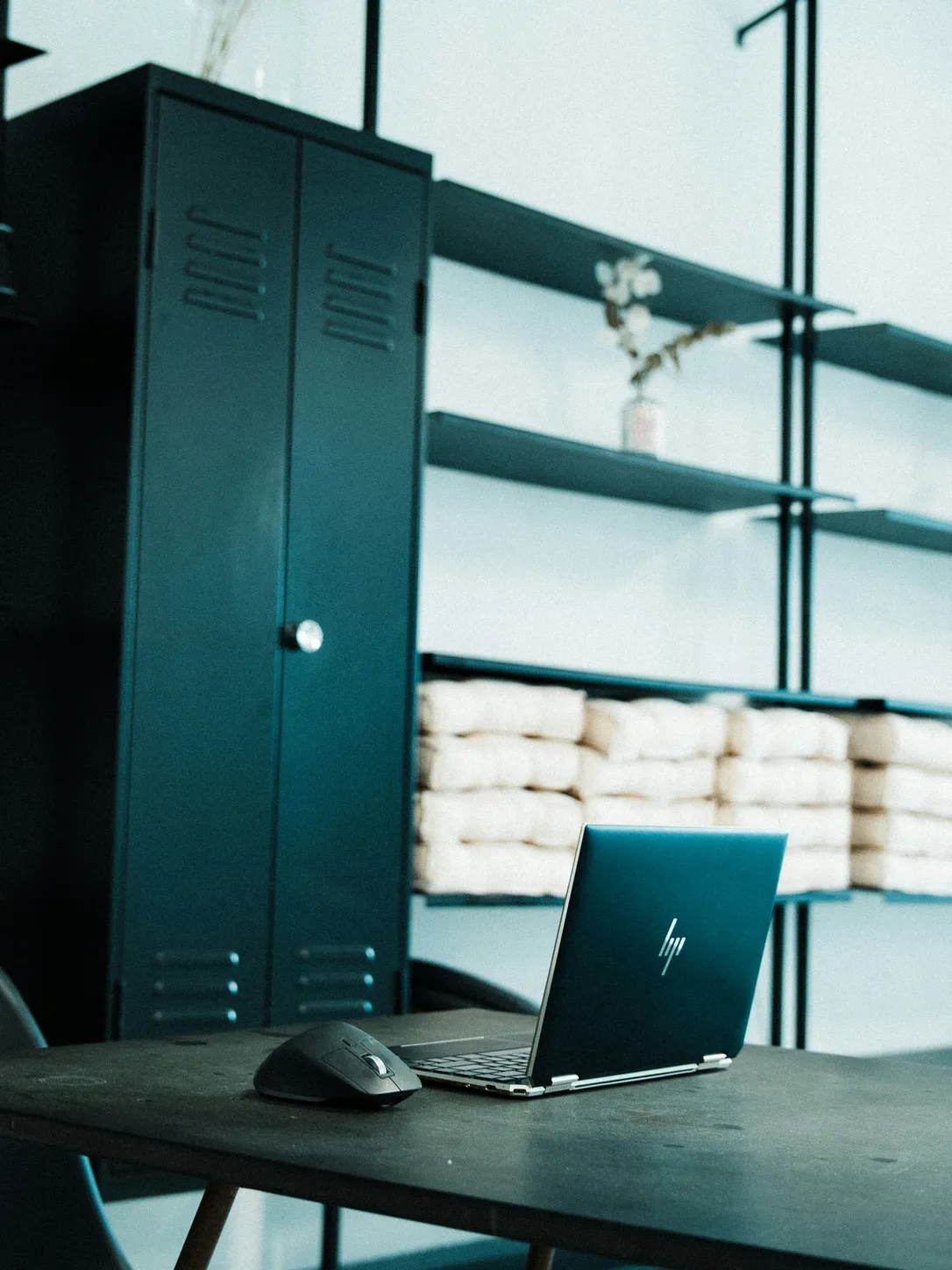 Ordinateur portable HP sur un bureau en bois dans un espace de travail moderne avec étagères de rangement en arrière-plan