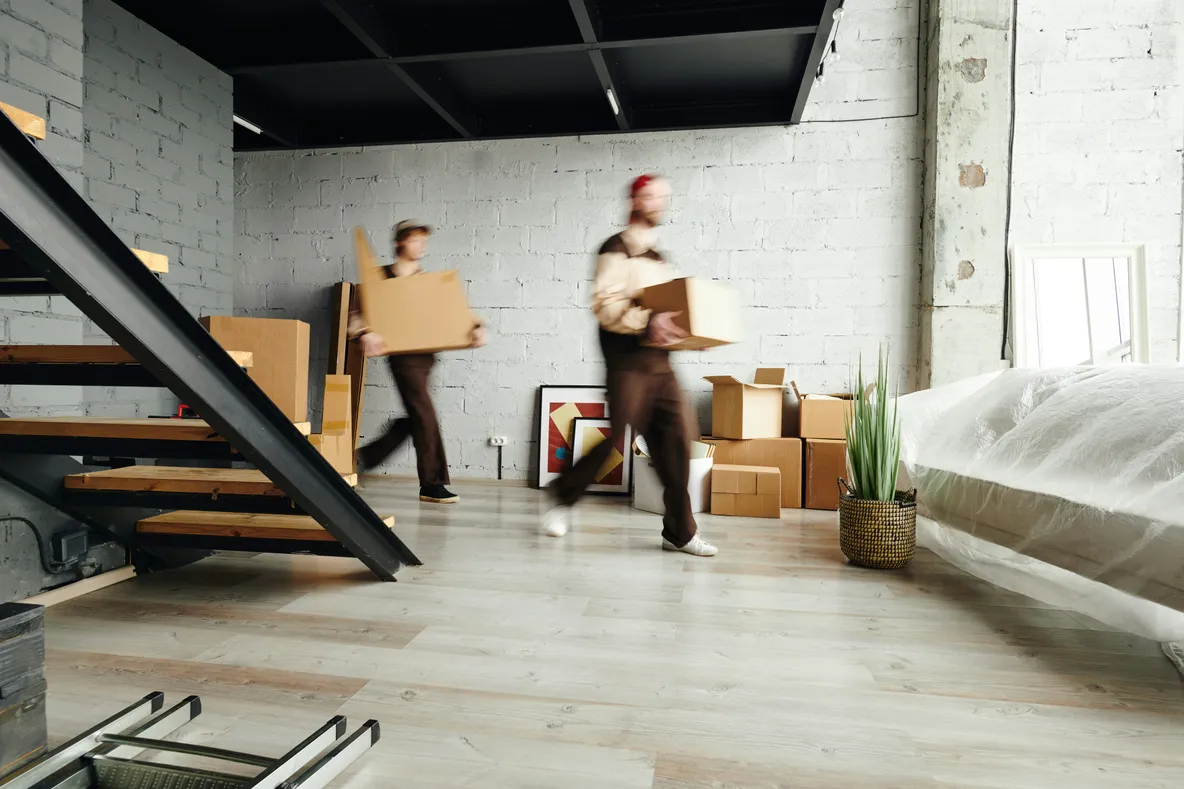 Deux techniciens transportant des cartons de matériel informatique dans un bureau moderne lors d'une installation