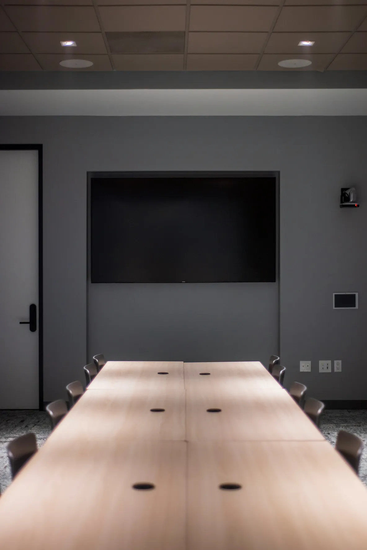 Salle de réunion moderne et minimaliste avec grand écran de présentation mural et table de conférence design