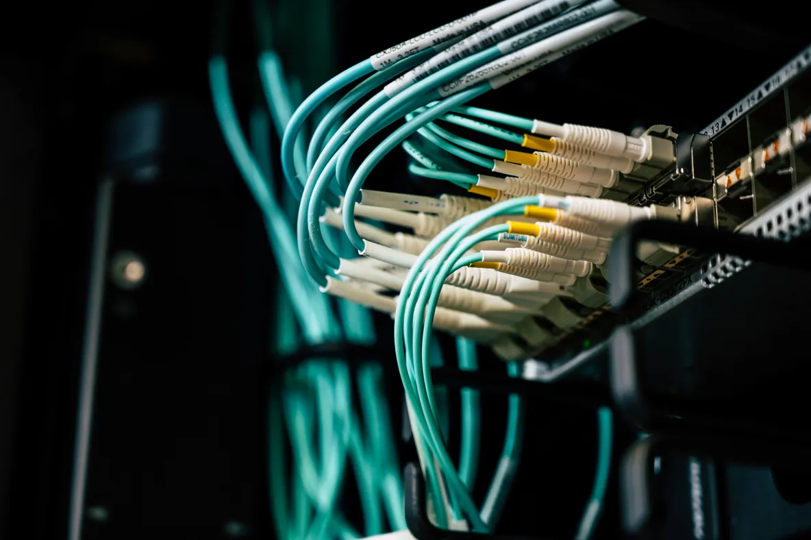 Câbles réseau à fibre optique turquoise connectés à un panneau de brassage dans un datacenter professionnel